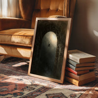 The Spider at the Pale Threshold, a spider sitting at the center of a pale arched glow inside a dark web, painted in sepia, olive and bone, in a wood frame beside a leather armchair and a stack of books