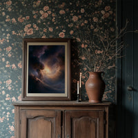 The Storm Keeps a Gold Heart, dark storm clouds piling over an open field with a warm amber glow burning at their center, in a dark frame on a wooden dresser against floral wallpaper