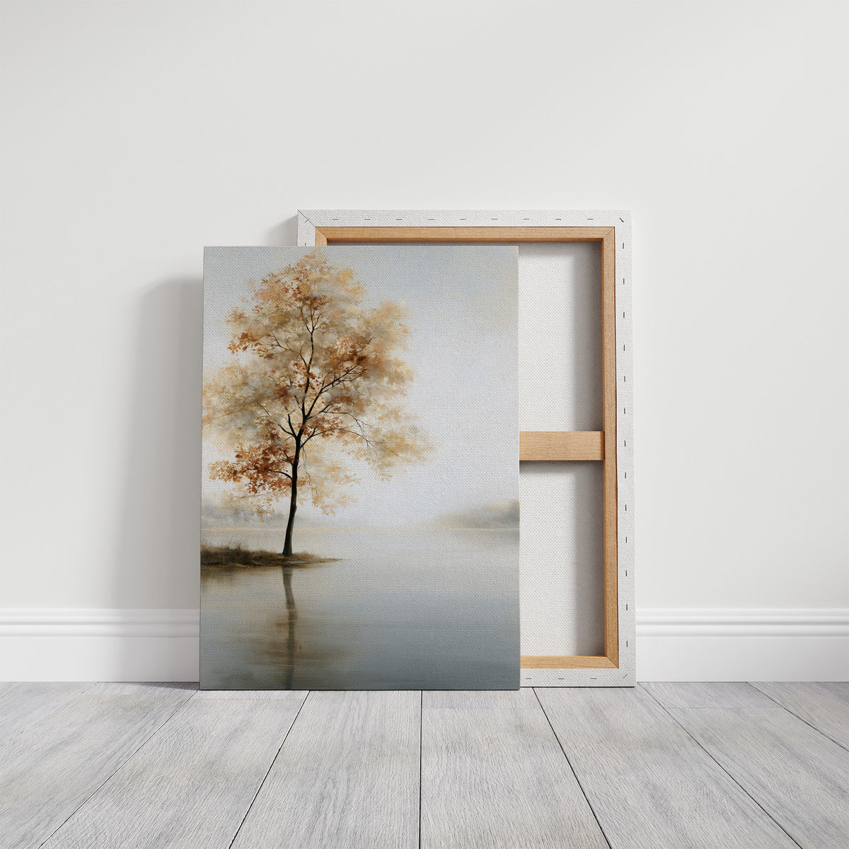 The Tree Stays Put in the Mist, a single tree with autumn gold in its crown standing on the edge of a pale lake, with the mist rolling low over the water and the sky a soft cream and blue, on a gallery canvas with wrapped edges leaning against a white wall
