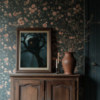 The Treehouse Never Sleeps, a glowing treehouse window high in a twisted oak under a blue fog of night, painted in deep teal and fog blue, in a dark frame on a wooden dresser against floral wallpaper