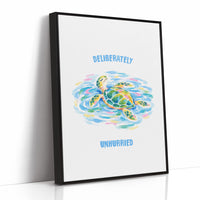The Turtle Keeps Its Own Time, a sea turtle drifting over pale blue and green watercolor waves, with two lines of bold blue lettering above and below it on a white ground, in a soft watercolor style, as a framed canvas in a black frame