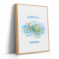 The Turtle Keeps Its Own Time, a sea turtle drifting over pale blue and green watercolor waves, with two lines of bold blue lettering above and below it on a white ground, in a soft watercolor style, as a framed canvas in a natural wood frame