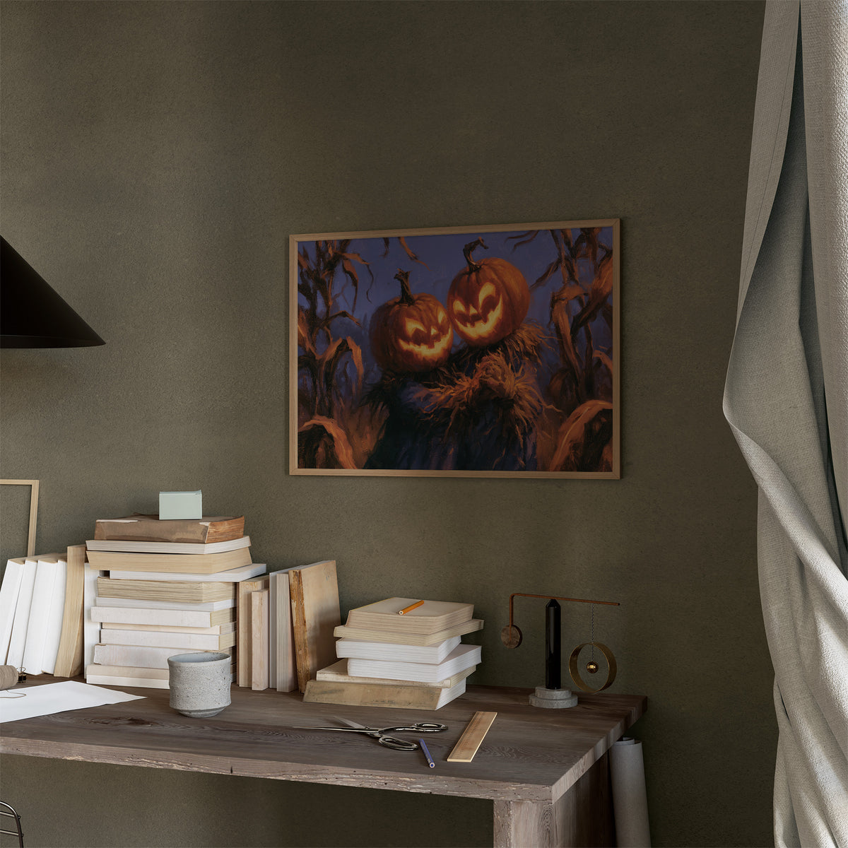 Two Lanterns Keeping Watch, two carved pumpkins glowing at the end of a cornfield under a deep blue dusk, painted in indigo, cornfield gold and warm orange, in a thin wood frame on a moss green wall above a desk stacked with books