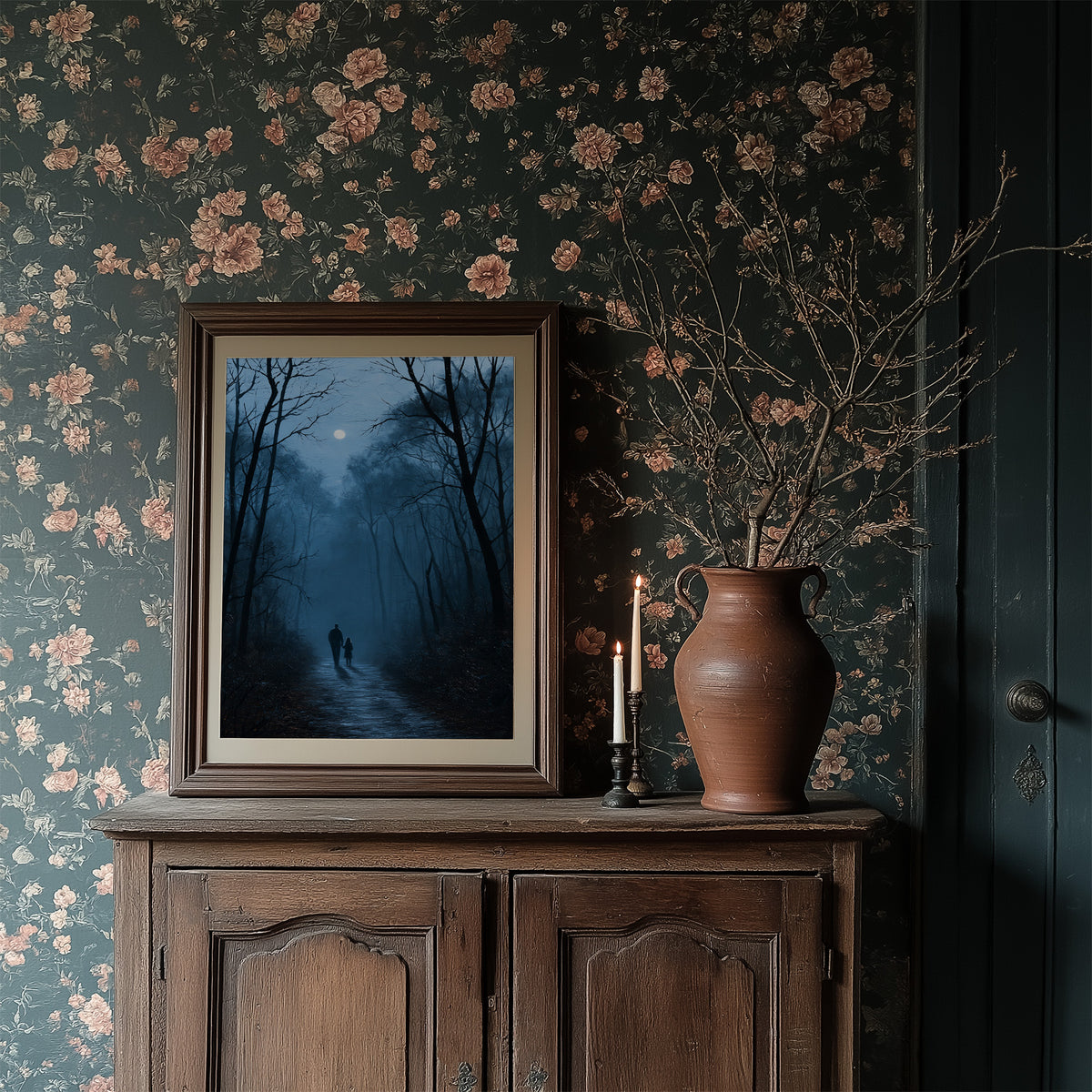 Two Shadows Take the Long Road, two dark figures walking a misty forest path between tall bare trees under a pale moon, painted in midnight blue, fog gray and soft silver, in a dark frame on a wooden dresser against floral wallpaper