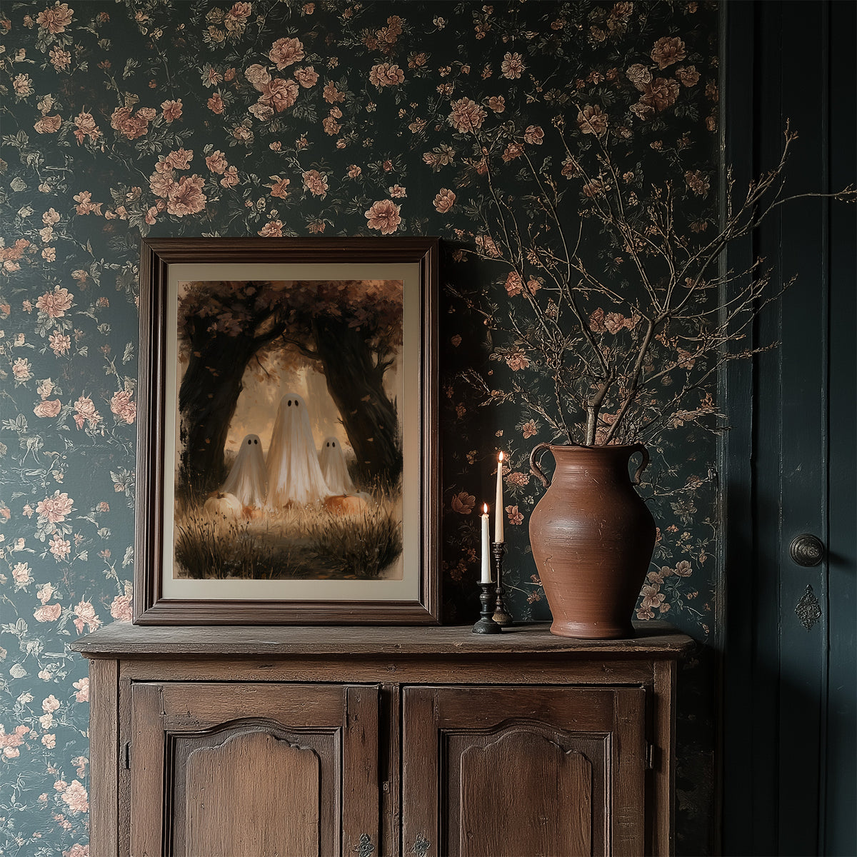 Two Visitors Under the Arch, two pale ghosts standing under an arch of dark trees above a field of tall grass and fallen leaves, painted in deep brown, bone and moss, in a dark wood frame on a floral wallpaper wall above a rustic cabinet and a vase