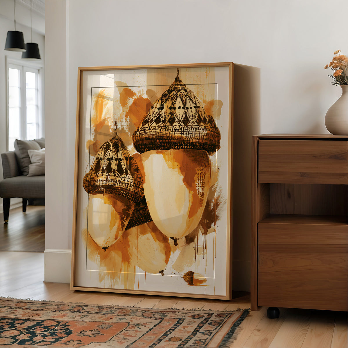 Where the Acorns Hold Their Amber, painterly oak nuts with carved caps and drips of ochre and cream on a pale ground, in a wood frame on a wall beside a walnut cabinet and an open doorway