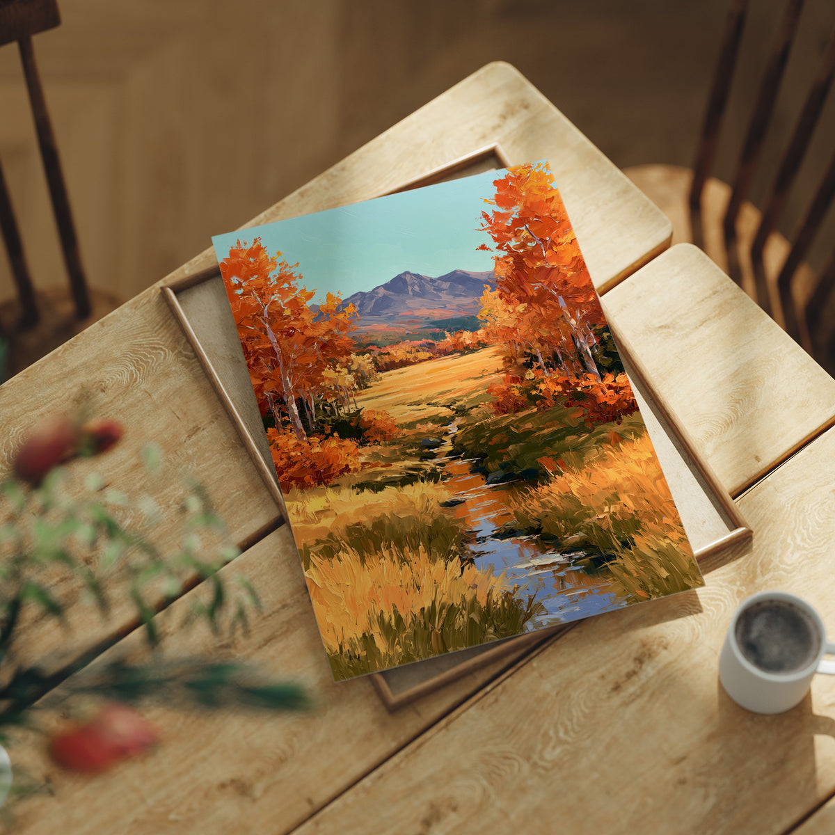 Where the Valley Turns Amber, an autumn valley of aspen trees in amber and rust beside a winding creek, with blue mountains and a pale sky above, painted in amber, rust and sky blue, lying flat on a light wood table beside a coffee cup and red berries