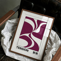 Where Two Curves Almost Touch, two maroon curved forms on a cream ground that lean toward each other and almost meet, with the word TENSION in black capitals and a small Japanese word beside it, in a wood frame on a black leather armchair beside crumpled white tissue