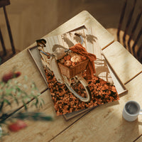 Gourd Delivery, Pedal Powered, print laid on a wooden table beside a white mug and flowers