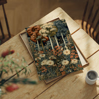 Daisy Chain Reaction In The Woods, print laid on a wooden table beside a white mug and flowers