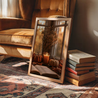 Candle Lit, Chapter Pending, framed print leaning on a leather armchair beside a stack of books