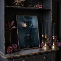 Shipshape It Is Not, large framed print leaning on a white wall beside a wood cabinet