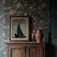 Bloom, Broom, And Feline Backup, framed print resting on a wooden chair beside sheer curtains